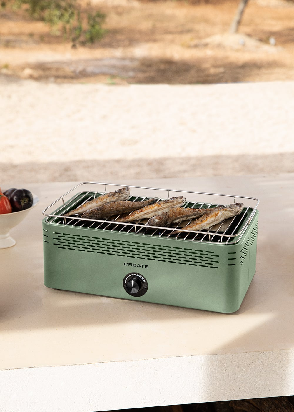 Una parrilla verde con cuatro peces asados encima, colocada al aire libre sobre una mesa.
