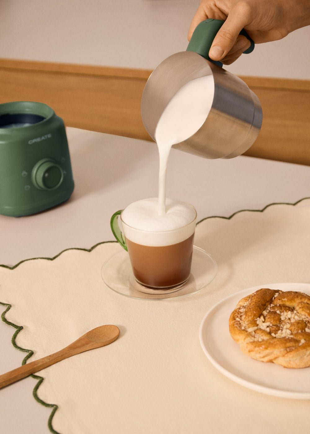 Se vierte leche en una taza de café, con un pastel cerca.