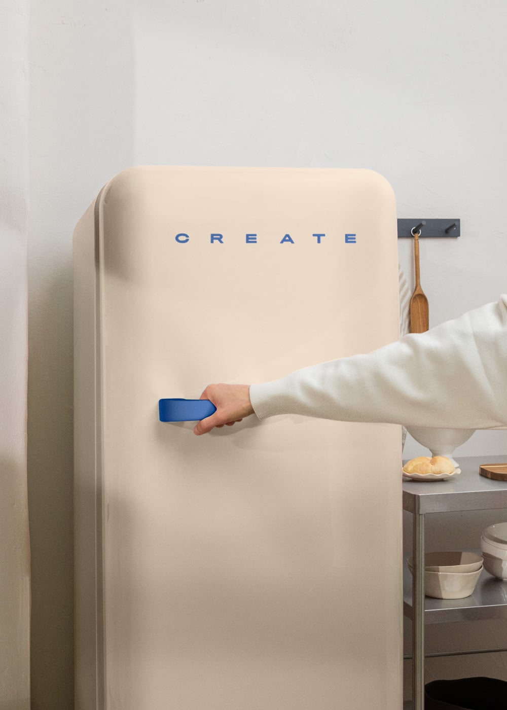 Una mano abre un refrigerador color crema con 'CREATE' escrito.