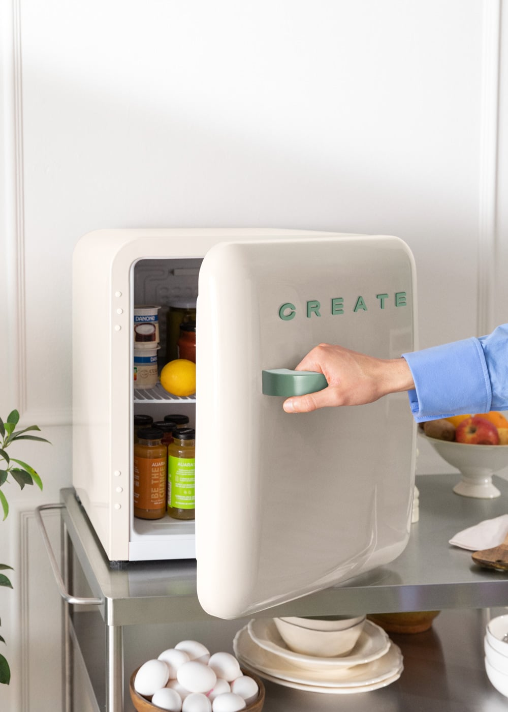 Una persona abre un mininevera beige con "CREATE" en la puerta.
