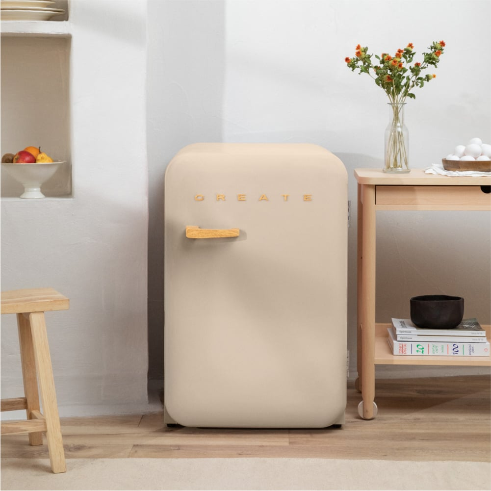 Un refrigerador color crema con asa de madera y la palabra CREATE en letras doradas.