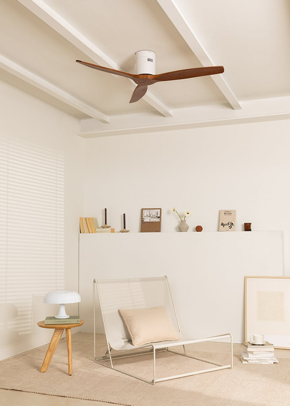 Una silla blanca y mesa auxiliar con lámpara en habitación minimalista con ventilador de techo.