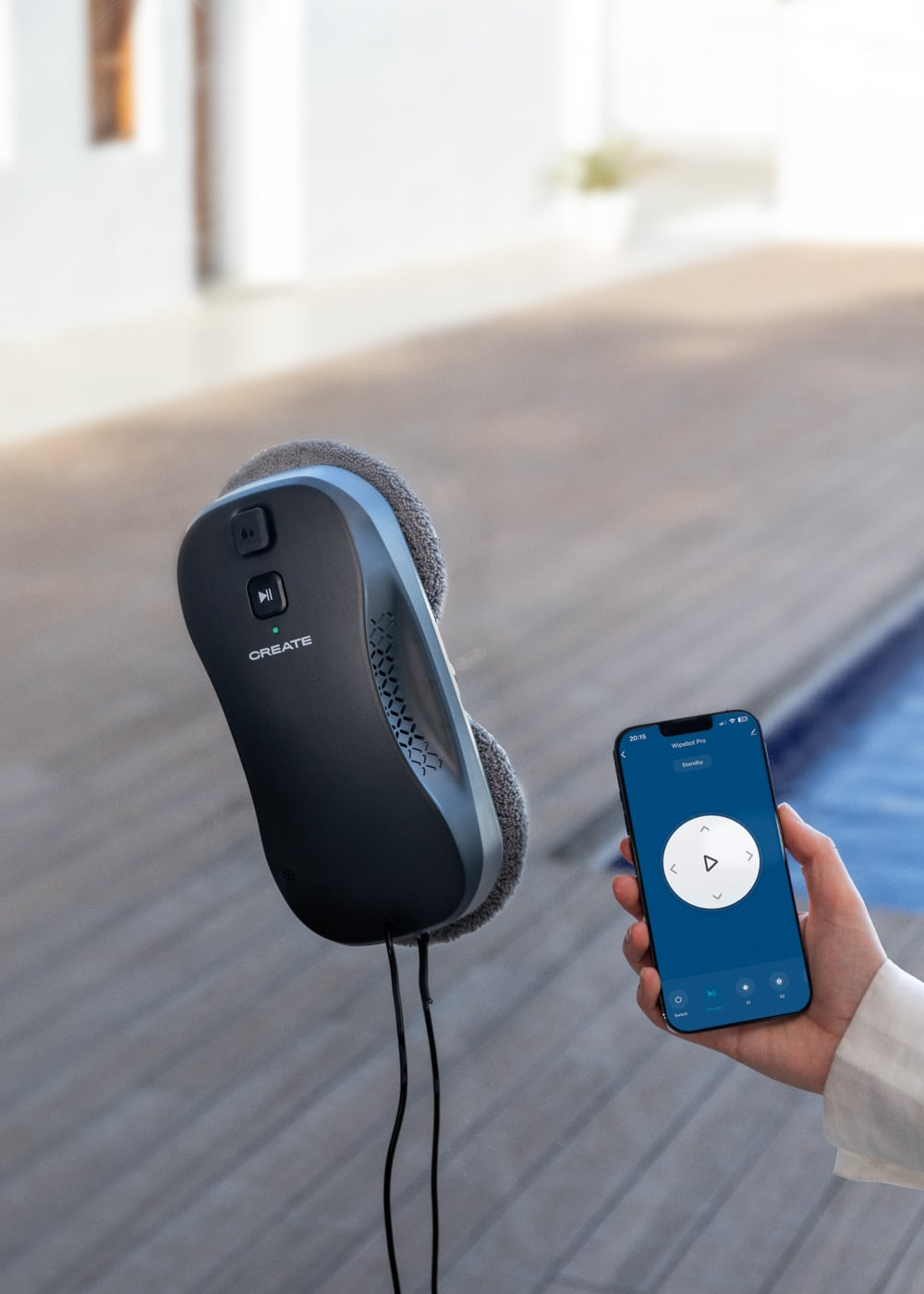 Un limpiacristales robotizado se adhiere a un panel de vidrio, junto a un smartphone.
