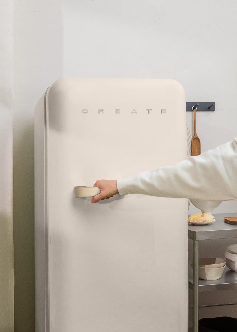 Una mano abre un refrigerador color crema con la palabra CREATE.