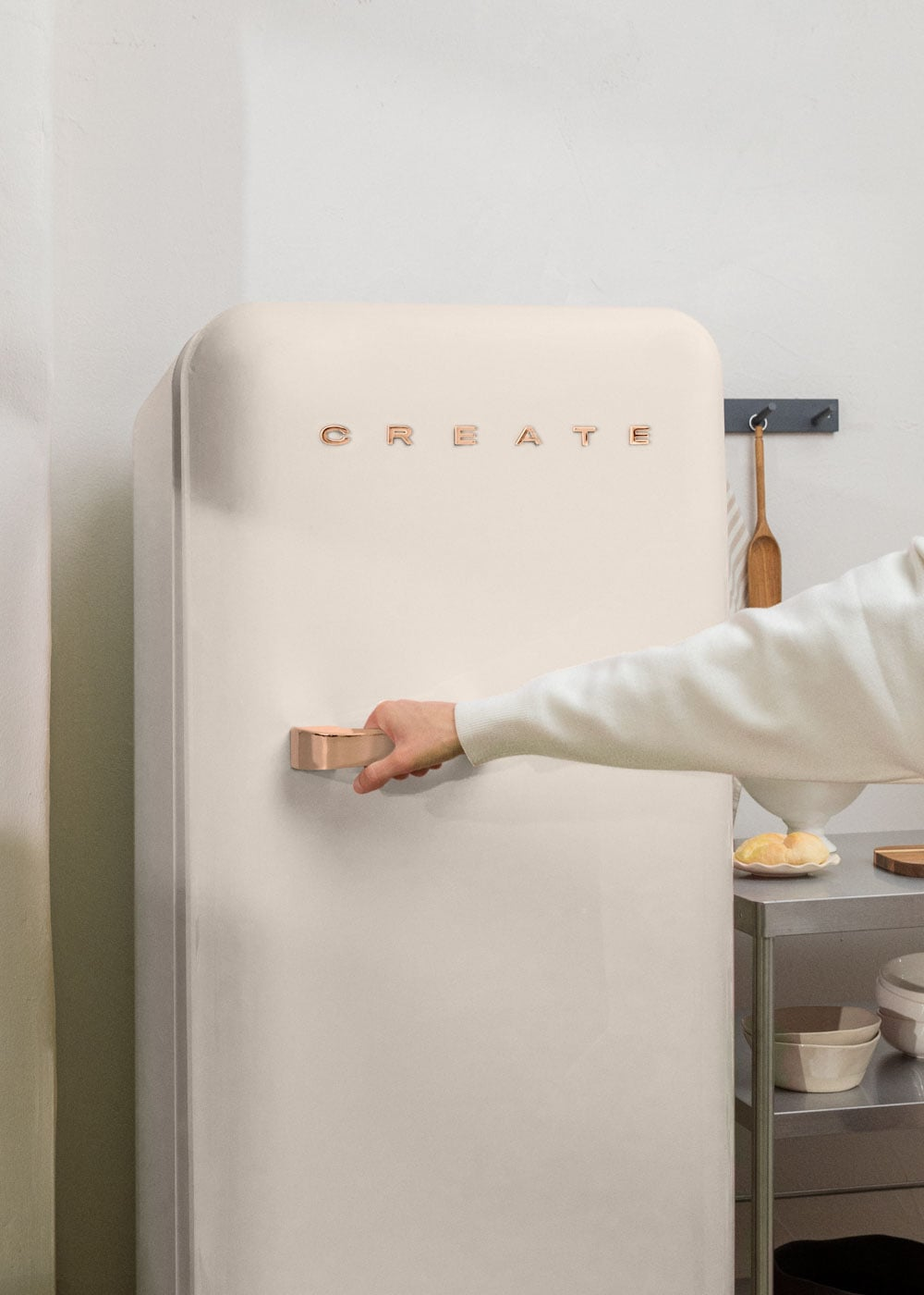 Una mano abre un refrigerador color crema con la inscripción "CREATE".