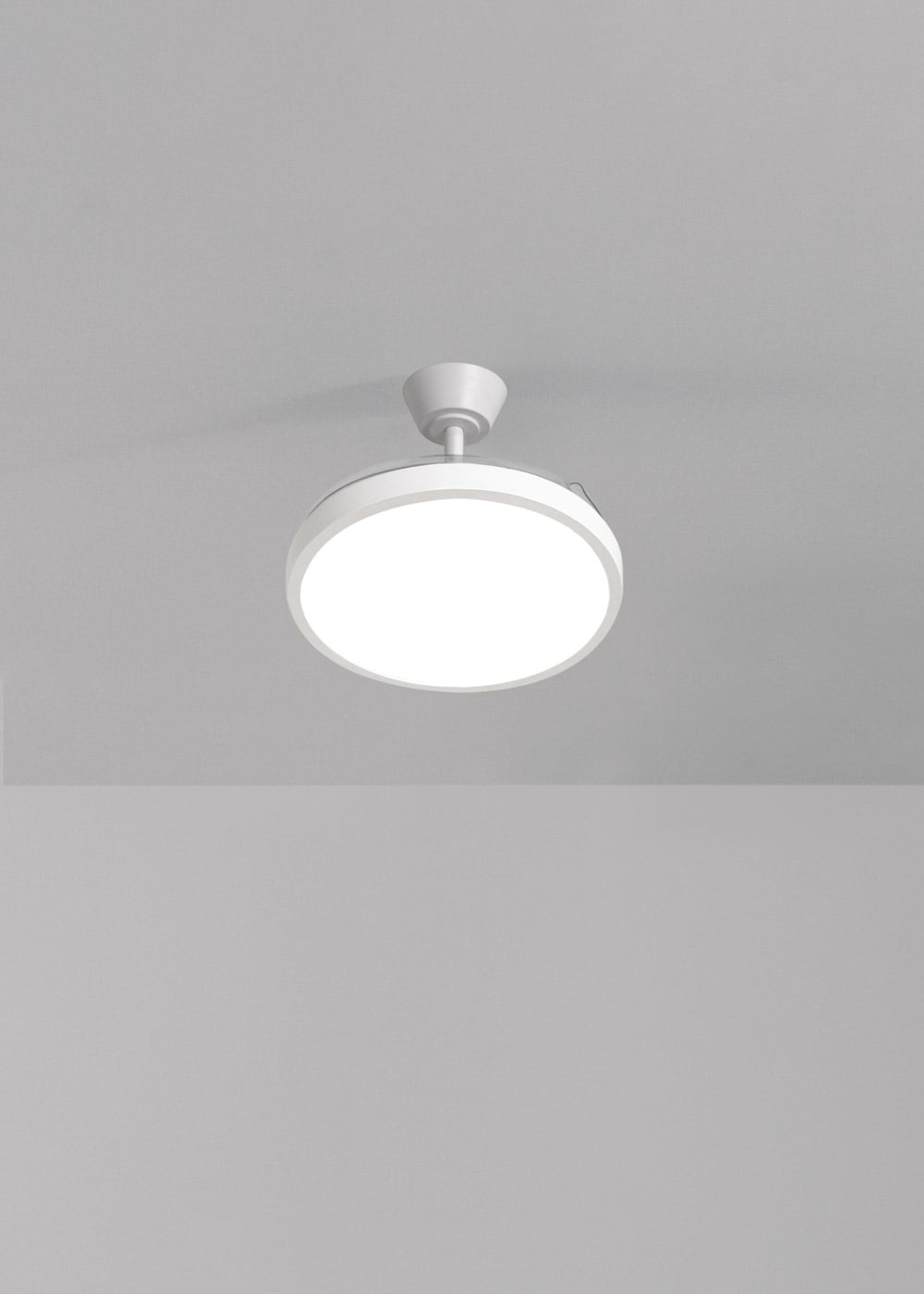 Una lámpara de techo blanca con ventilador, montada en un techo gris.