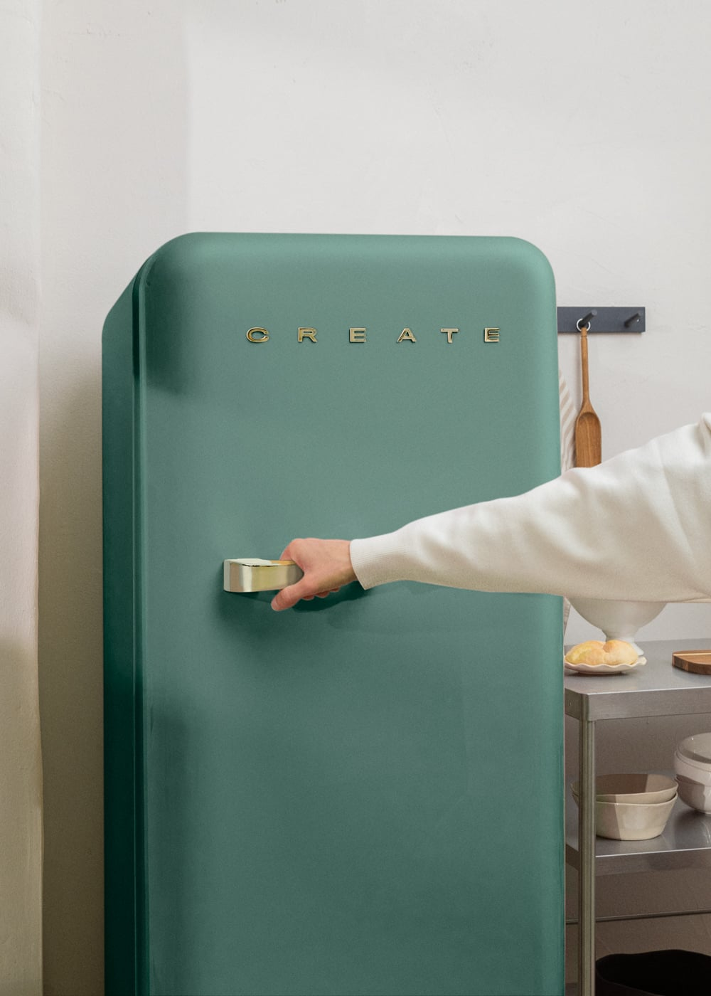Una mano abre un refrigerador verde azulado con la palabra CREATE.