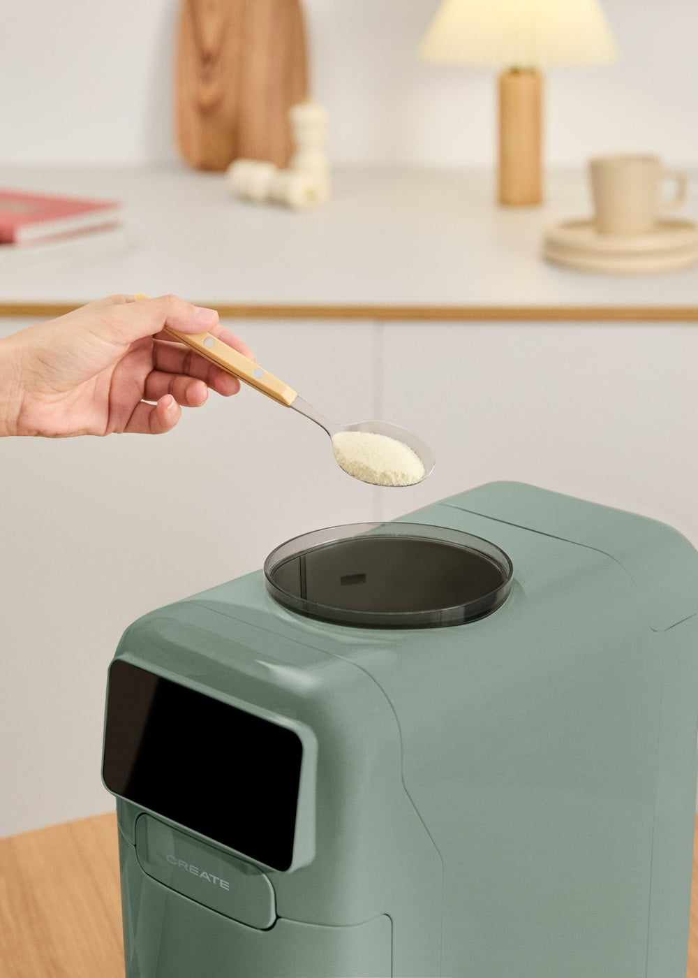 Una mano sostiene una cuchara con polvo blanco sobre un recipiente verde.