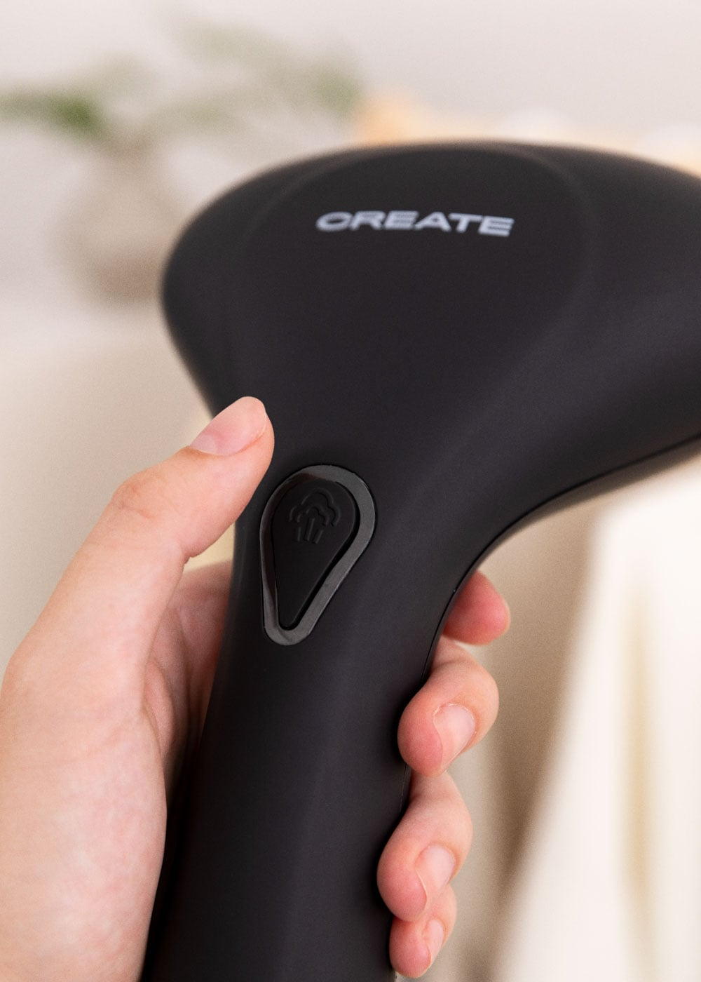 Una mano sostiene una plancha de vapor negra con el nombre CREATE.