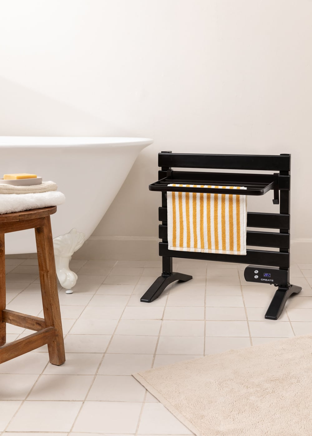 Un toallero eléctrico negro con toalla a rayas junto a una bañera.