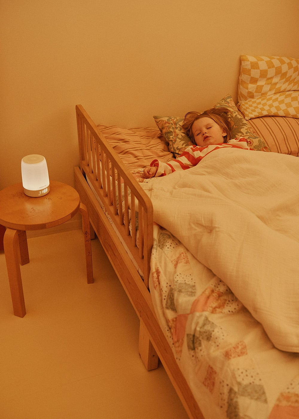 Un niño duerme en una cama con una luz nocturna en una mesita auxiliar.