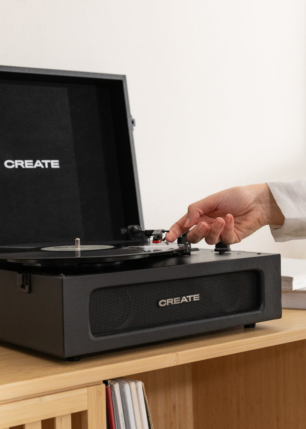 Una mano coloca una aguja en un disco de vinilo giratorio en un tocadiscos negro.