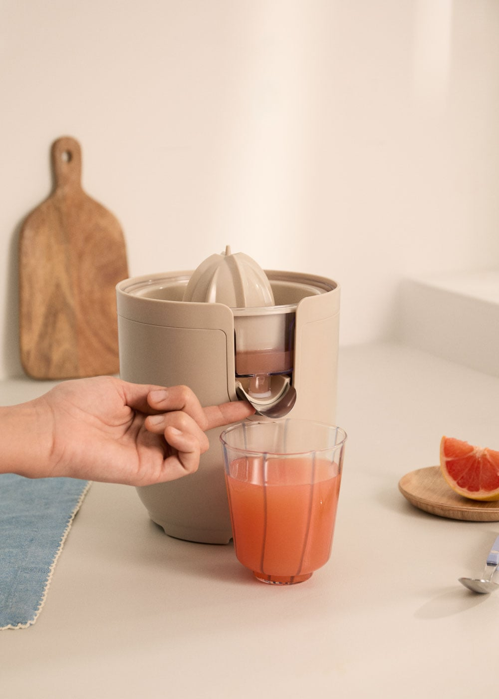 Una mano opera un exprimidor mientras el jugo se vierte en un vaso.