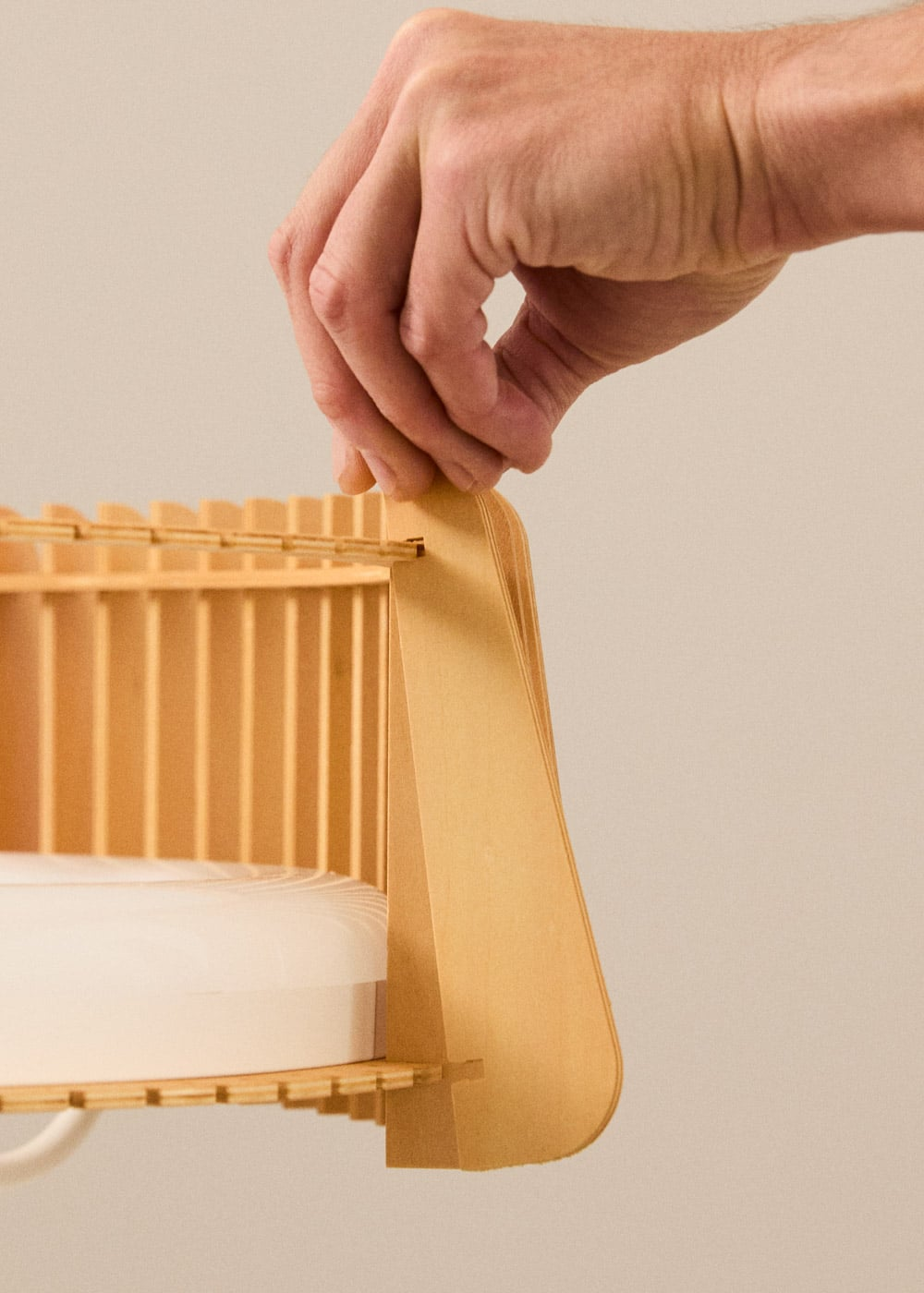 Una mano sujeta un estante de madera con un rollo blanco.