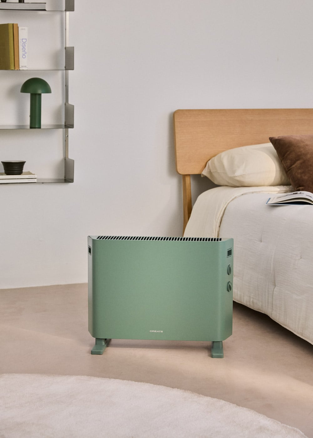 Un radiador verde está sobre una alfombra frente a una cama con cabecero de madera.