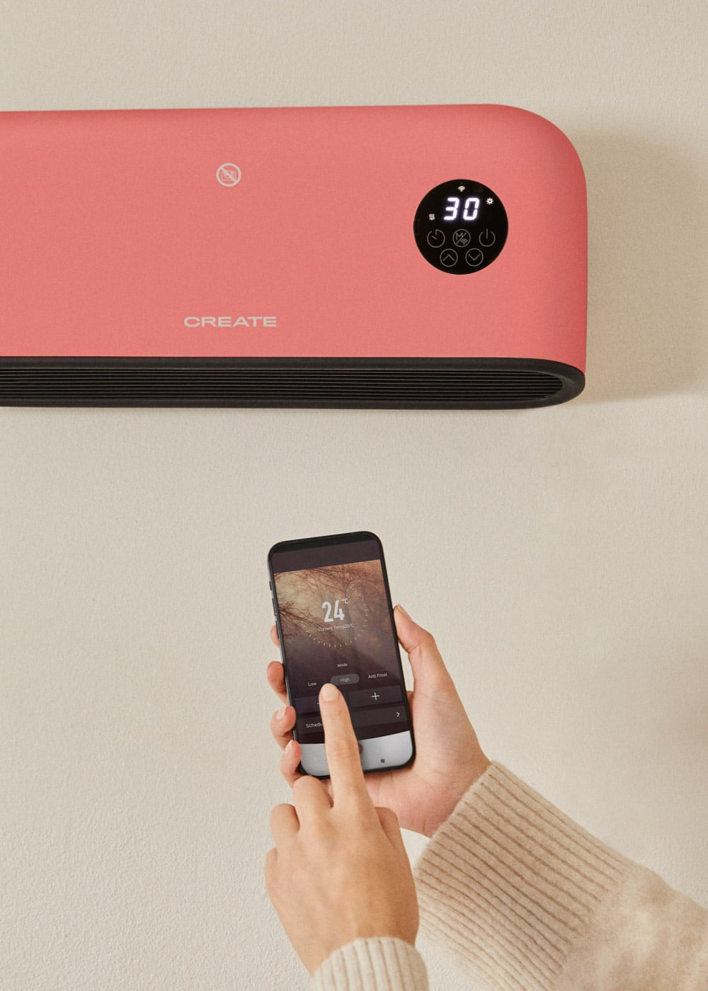 Una persona opera un radiador rosa con una aplicación de smartphone que muestra controles de temperatura.