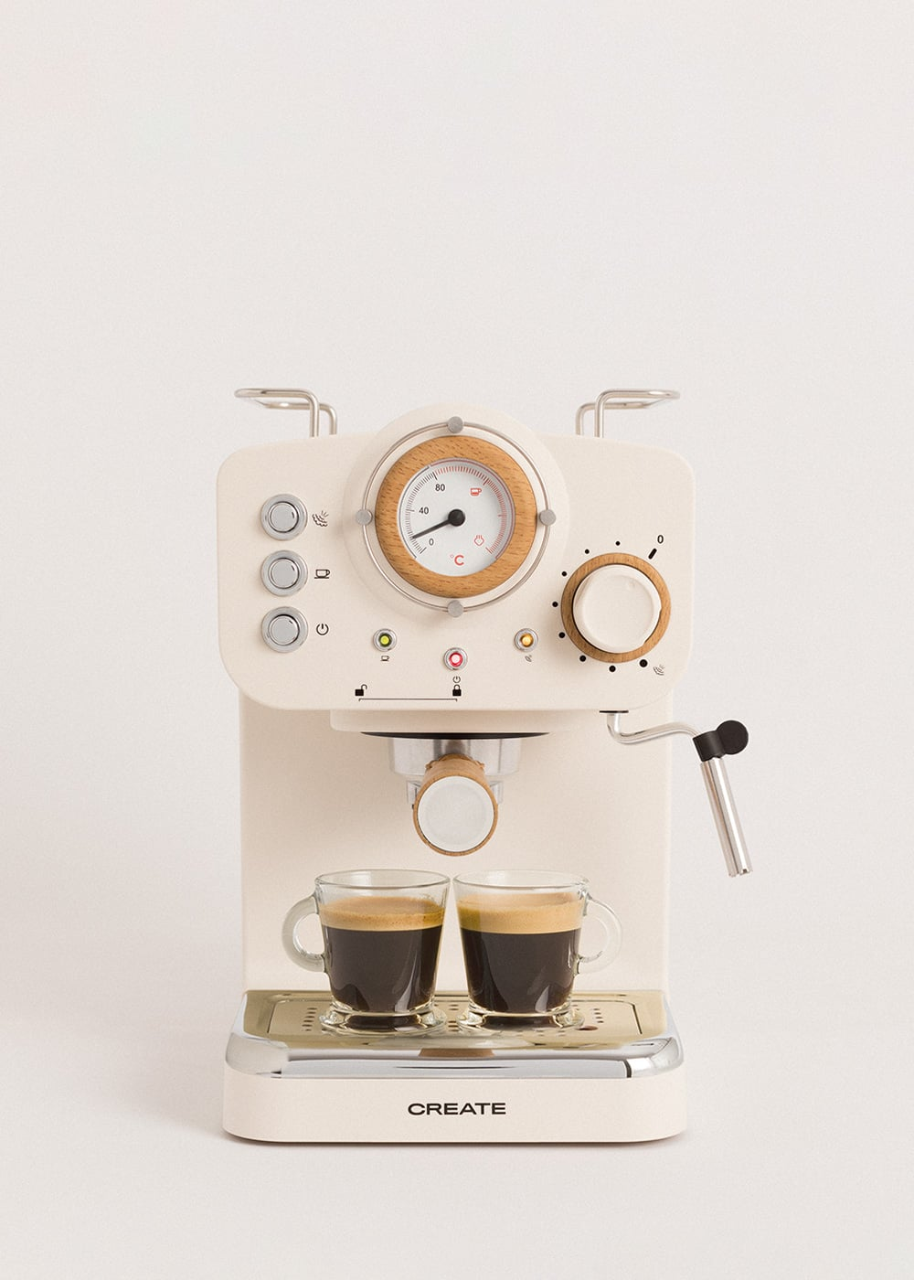 Una cafetera espresso color crema con dos tazas de espresso y un manómetro.
