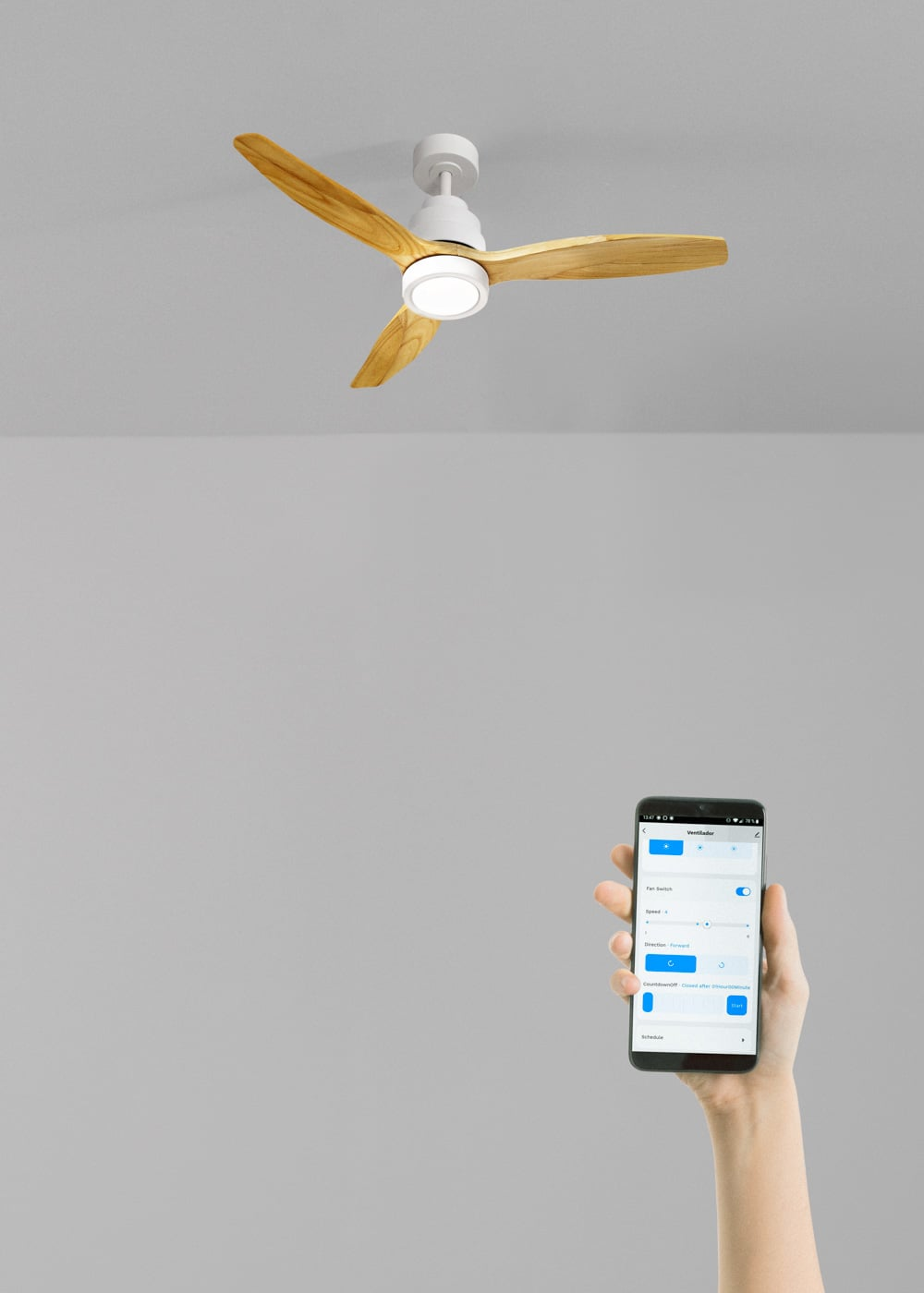 Un ventilador de techo con aspas de madera y luz es controlado por un smartphone.
