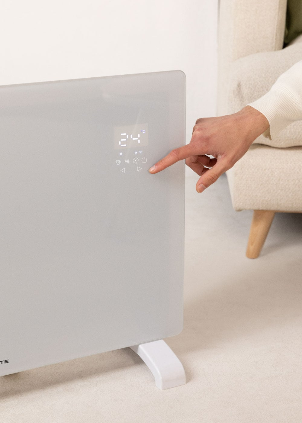 Una mano presiona el panel de control de un calentador con pantalla digital.