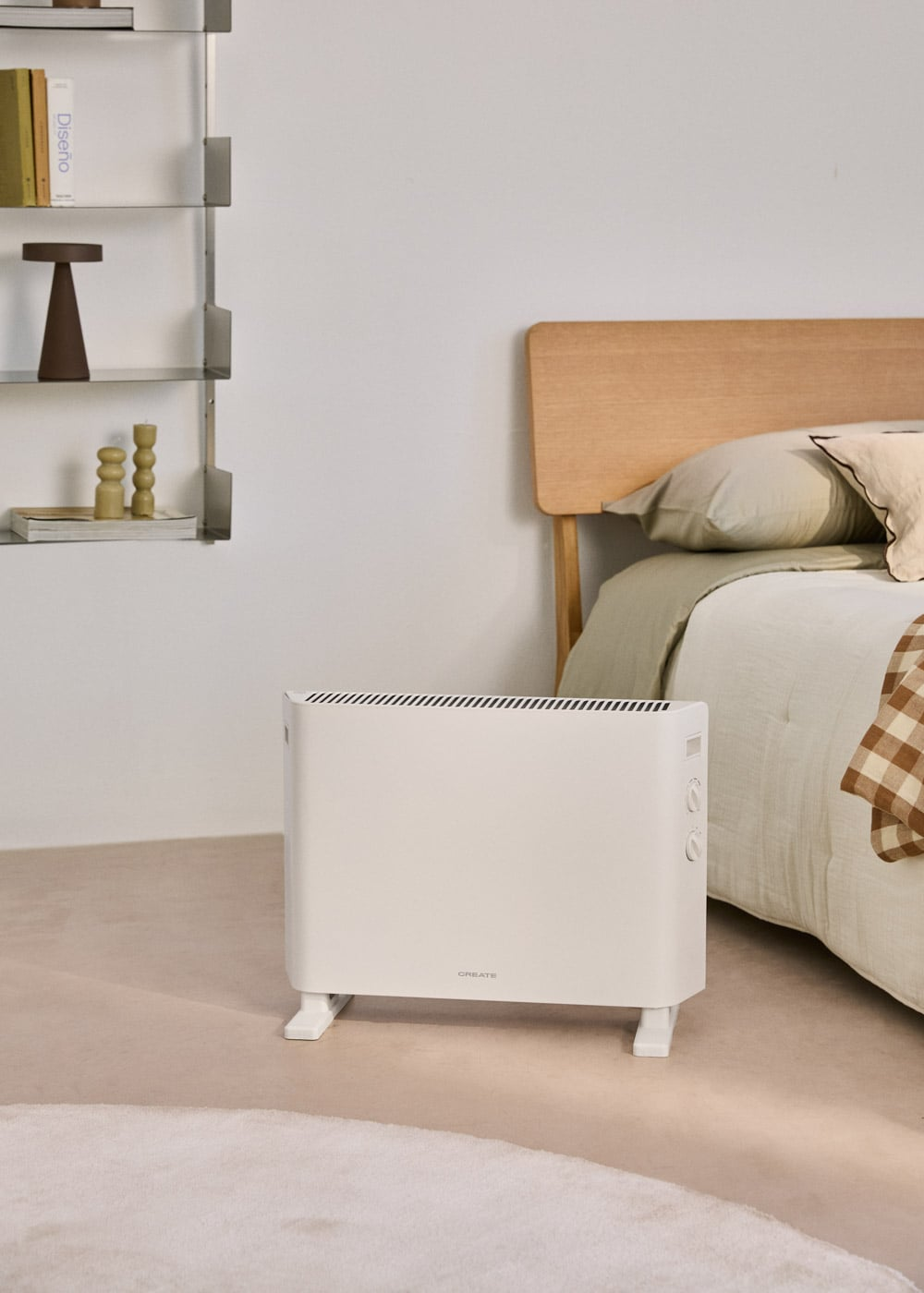 Un radiador blanco delante de una cama con cabecero de madera y manta a cuadros.