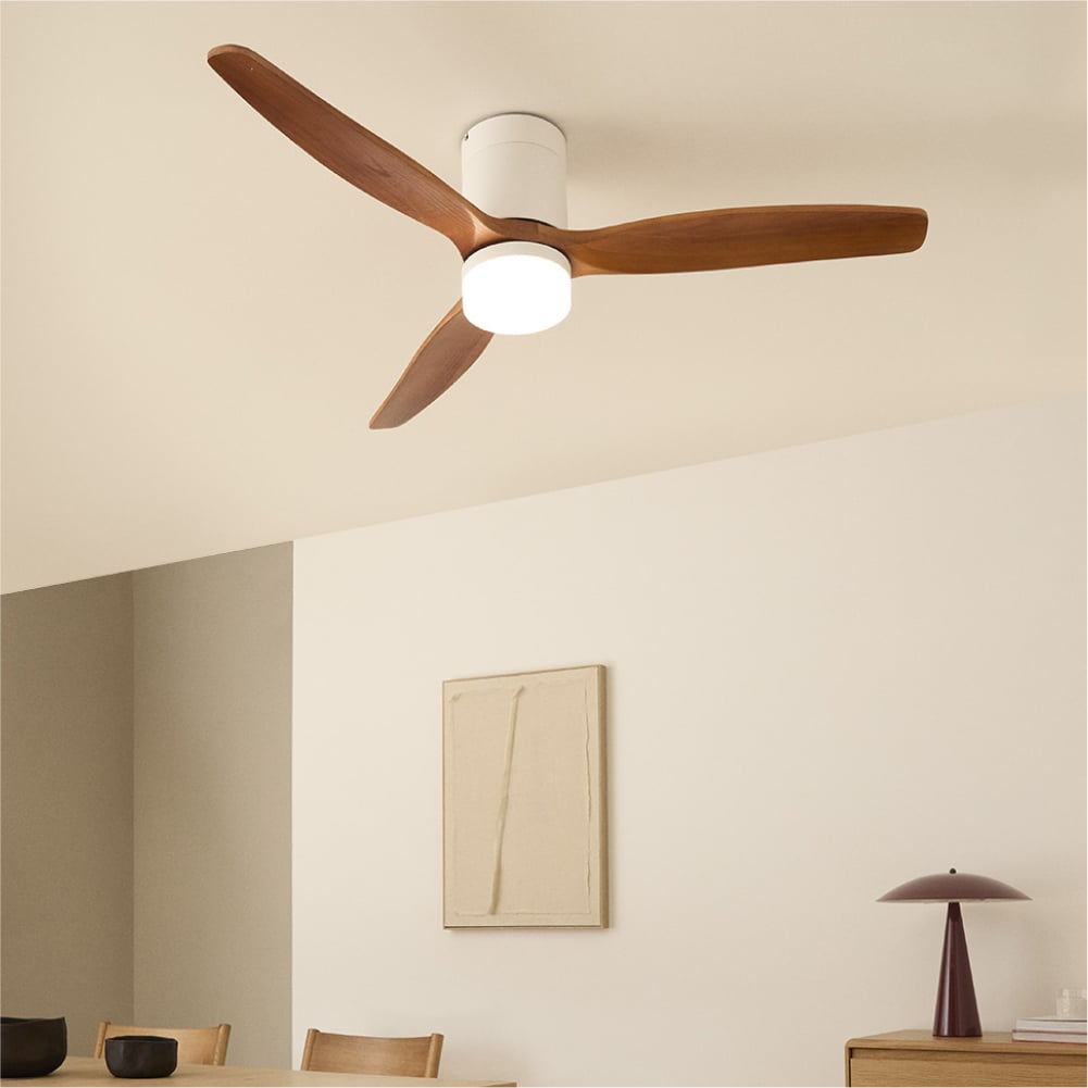 Ventilador de techo con aspas de madera y luz integrada sobre cuadro y mesa.