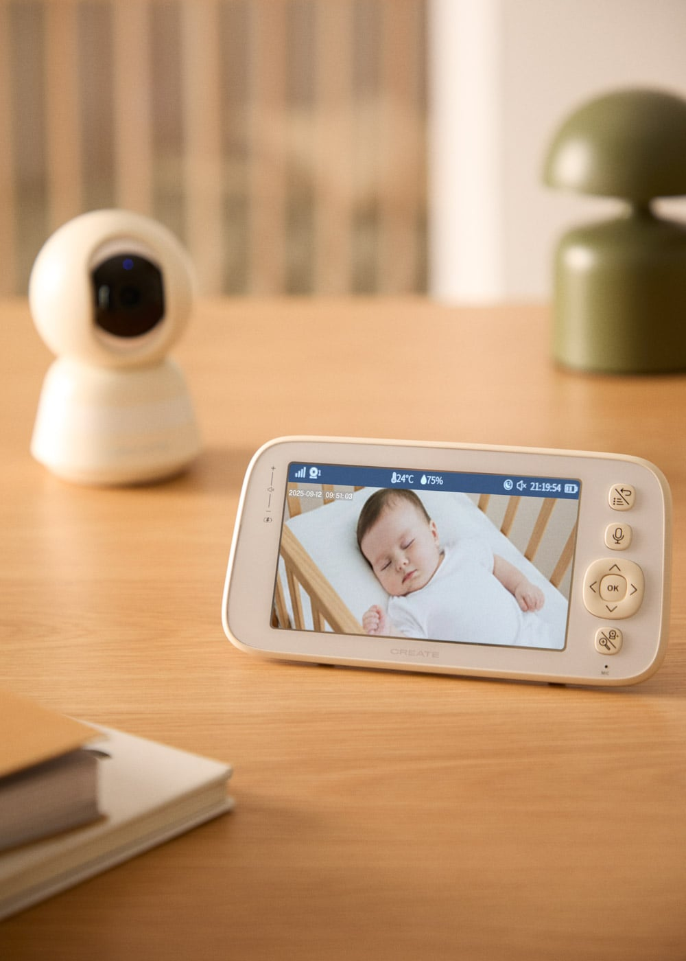 Un vigilabebés muestra un bebé durmiendo en una cuna. Una cámara blanca a la izquierda.