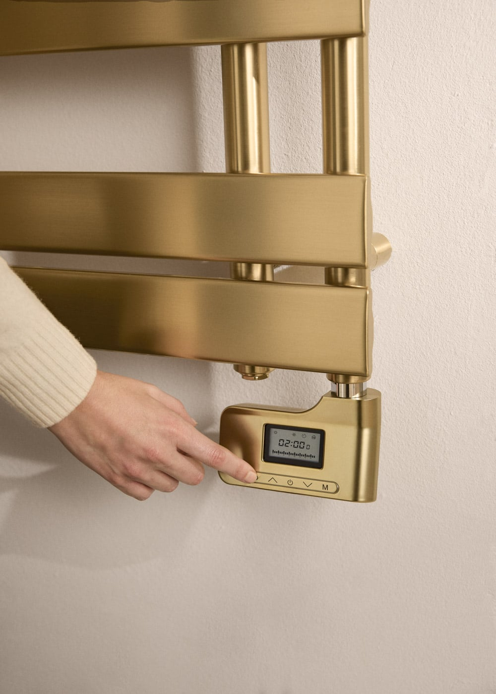 Una mano toca la pantalla digital de un toallero dorado.