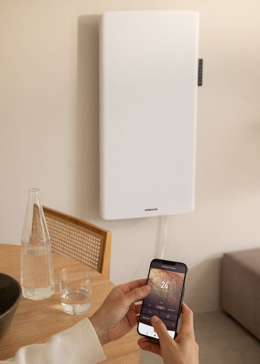 Una estufa blanca en una pared, controlada por un smartphone que muestra 24 grados.