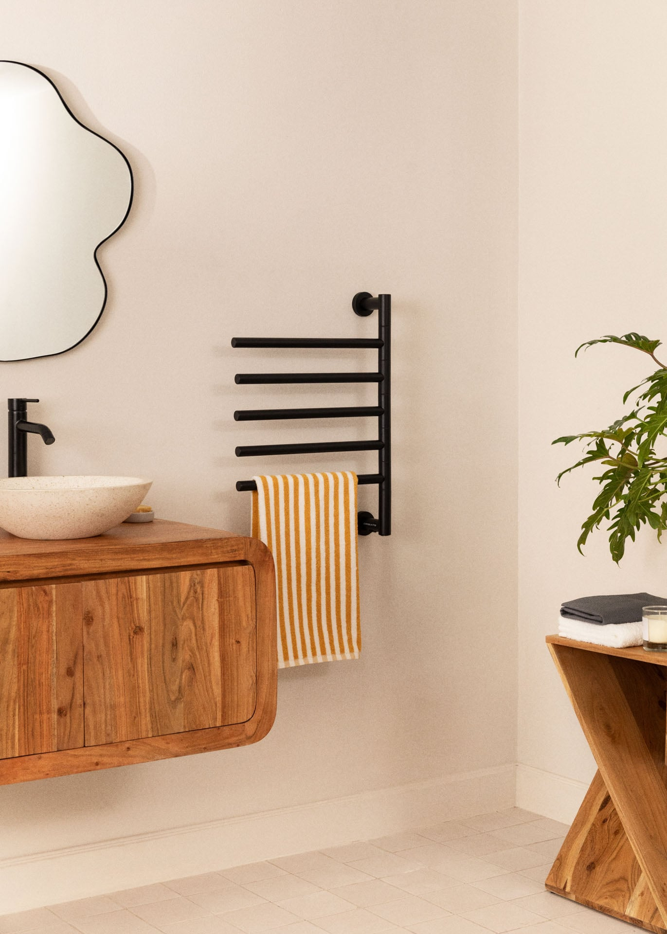 Una escena de baño con tocador de madera, espejo, toallero y planta.
