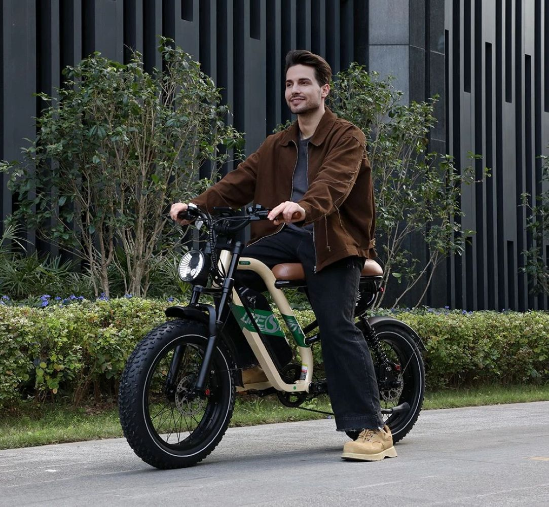 Un uomo guida una e-bike con pneumatici larghi davanti a un edificio moderno.