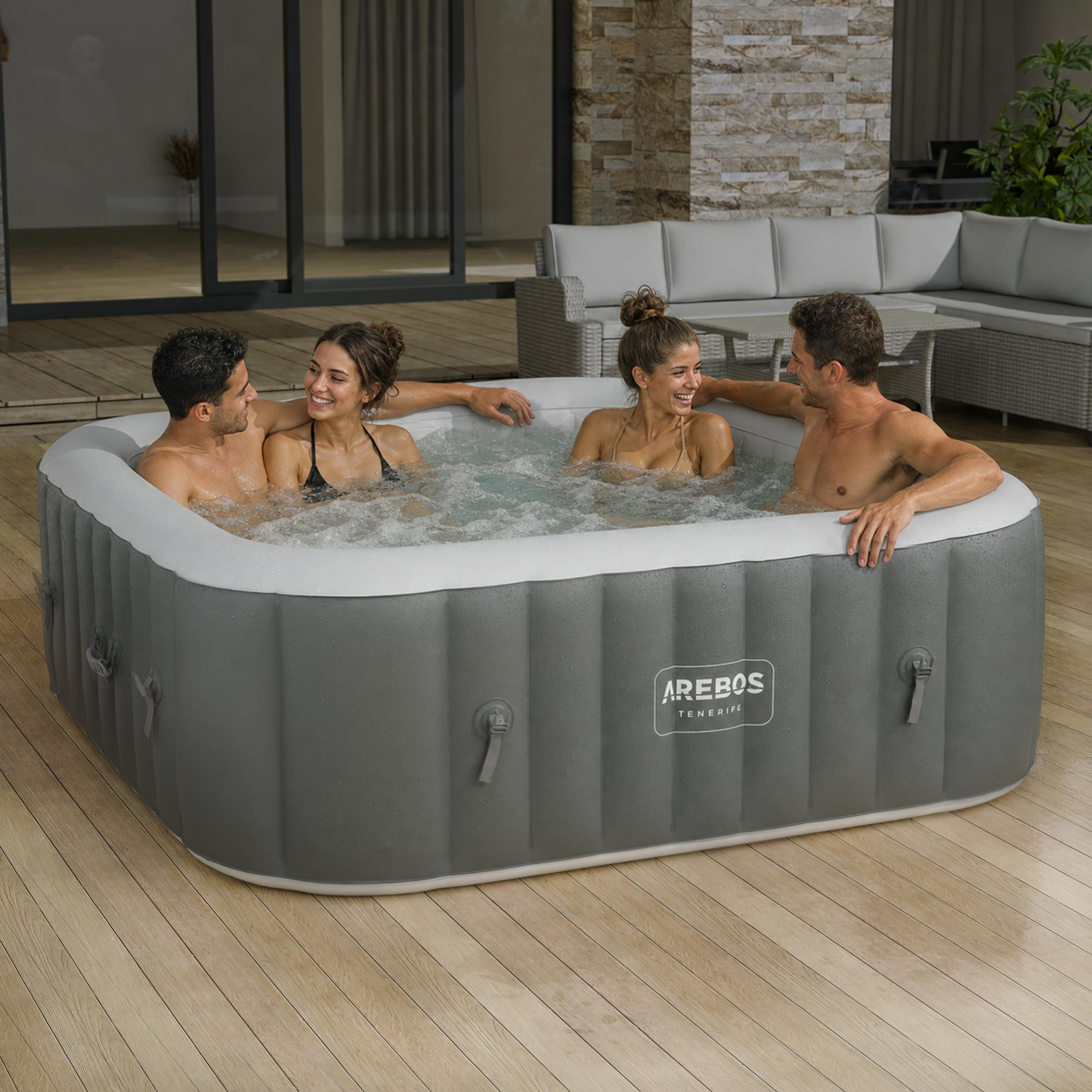 Vier Personen entspannen sich in einem aufblasbaren Whirlpool auf einer Holzterrasse.