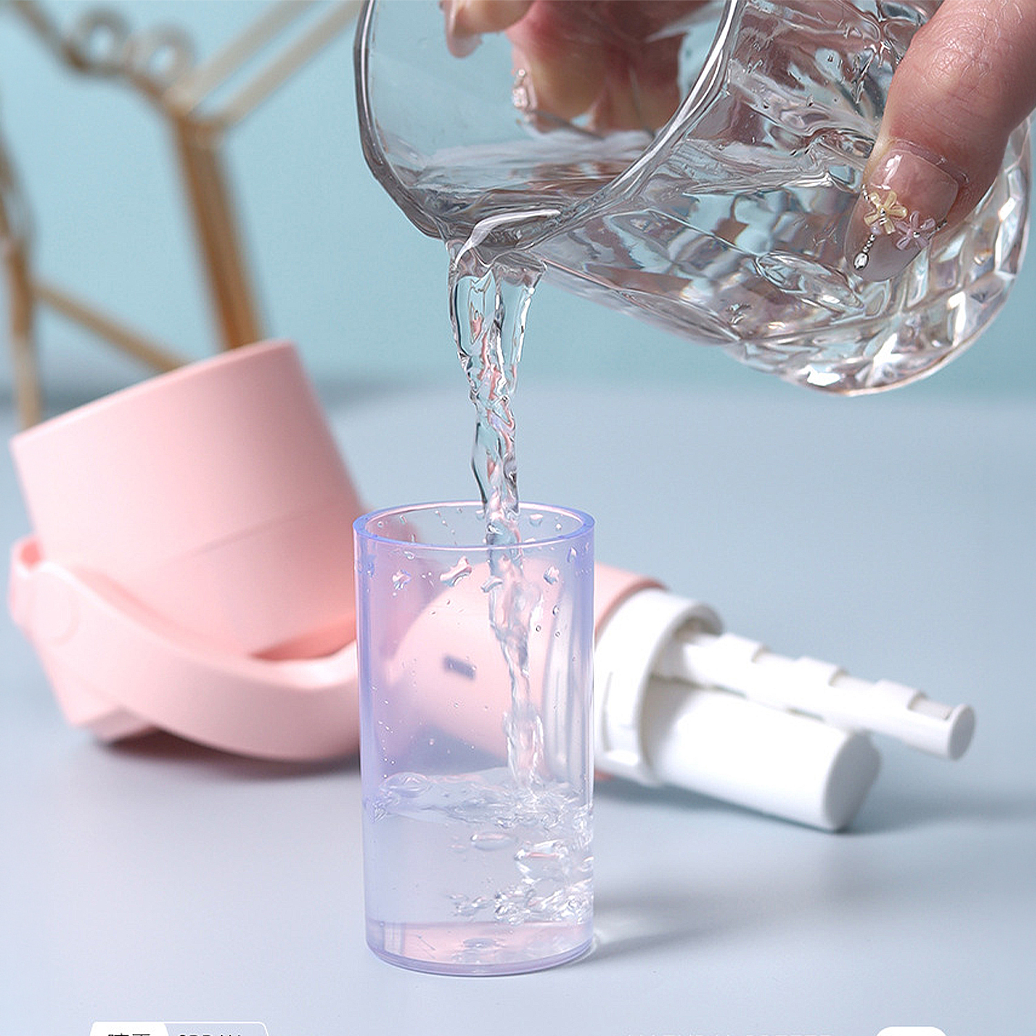 Líquido claro se vierte de un vaso a una taza pequeña y transparente. Dispositivo rosa al fondo.
