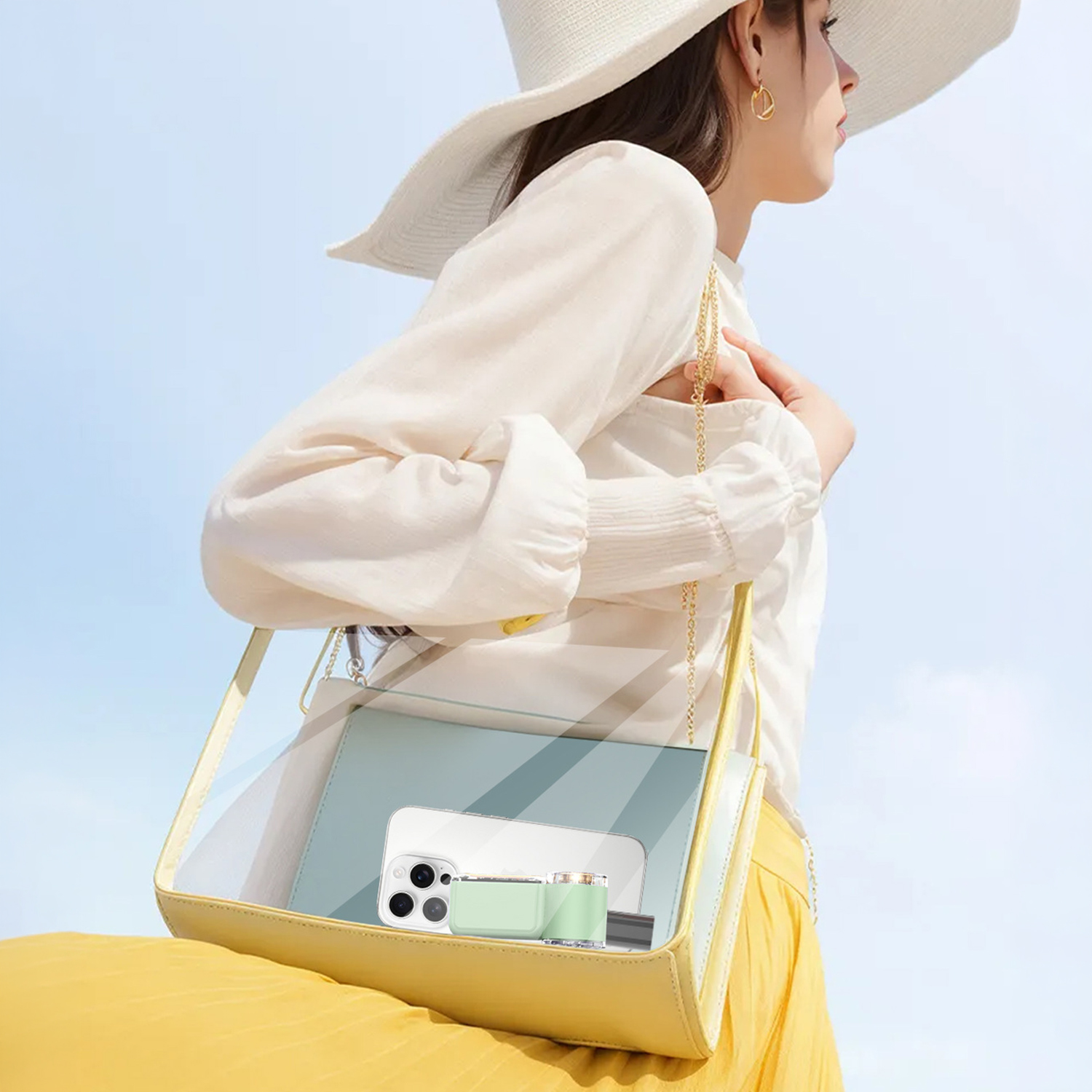 Mujer con sombrero, blusa blanca, bolso amarillo con teléfono y accesorio verde menta.