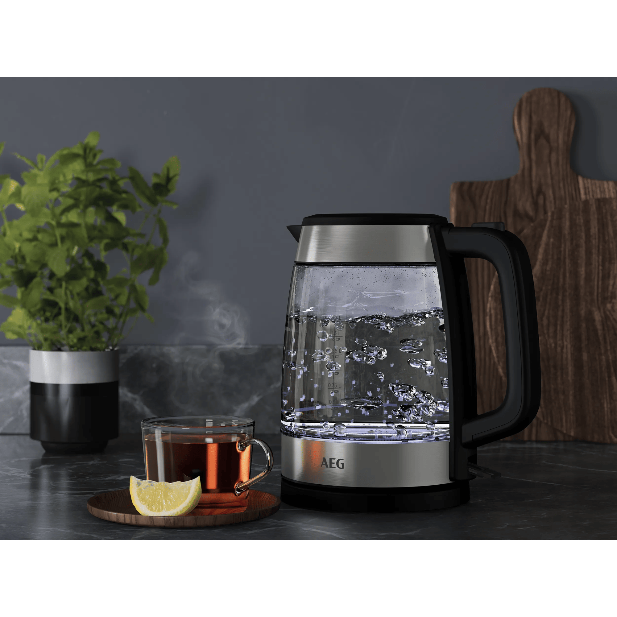 Ein Glaswasserkocher mit kochendem Wasser und eine Tasse Tee mit Zitrone.