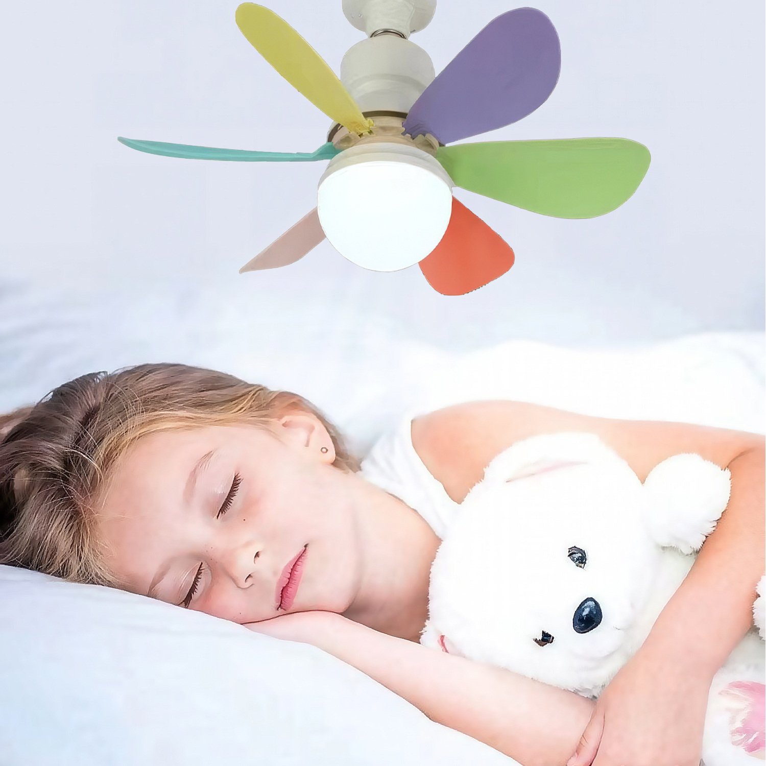 Una niña duerme plácidamente en la cama, abrazando un oso de peluche blanco. Un ventilador de techo colorido arriba.