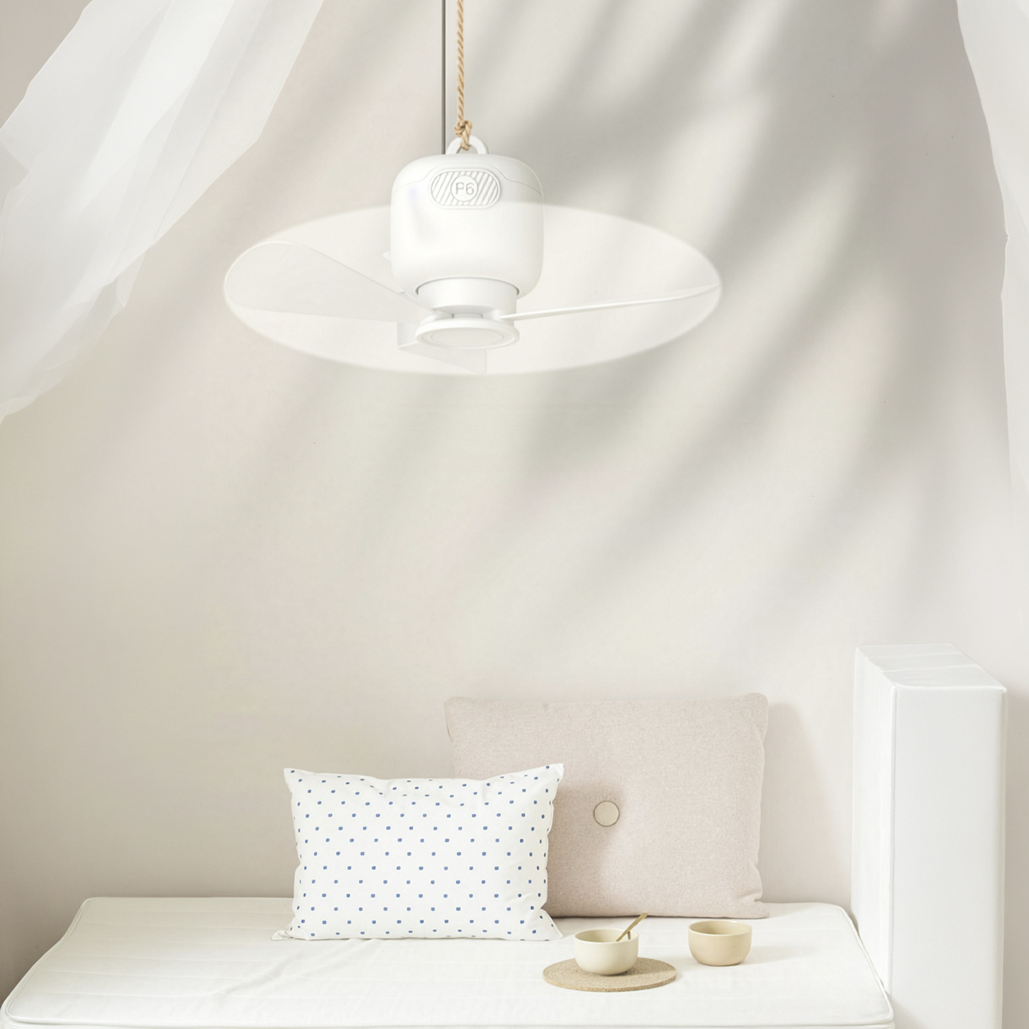 Un ventilador blanco colgando sobre una cama con cojines y cuencos.