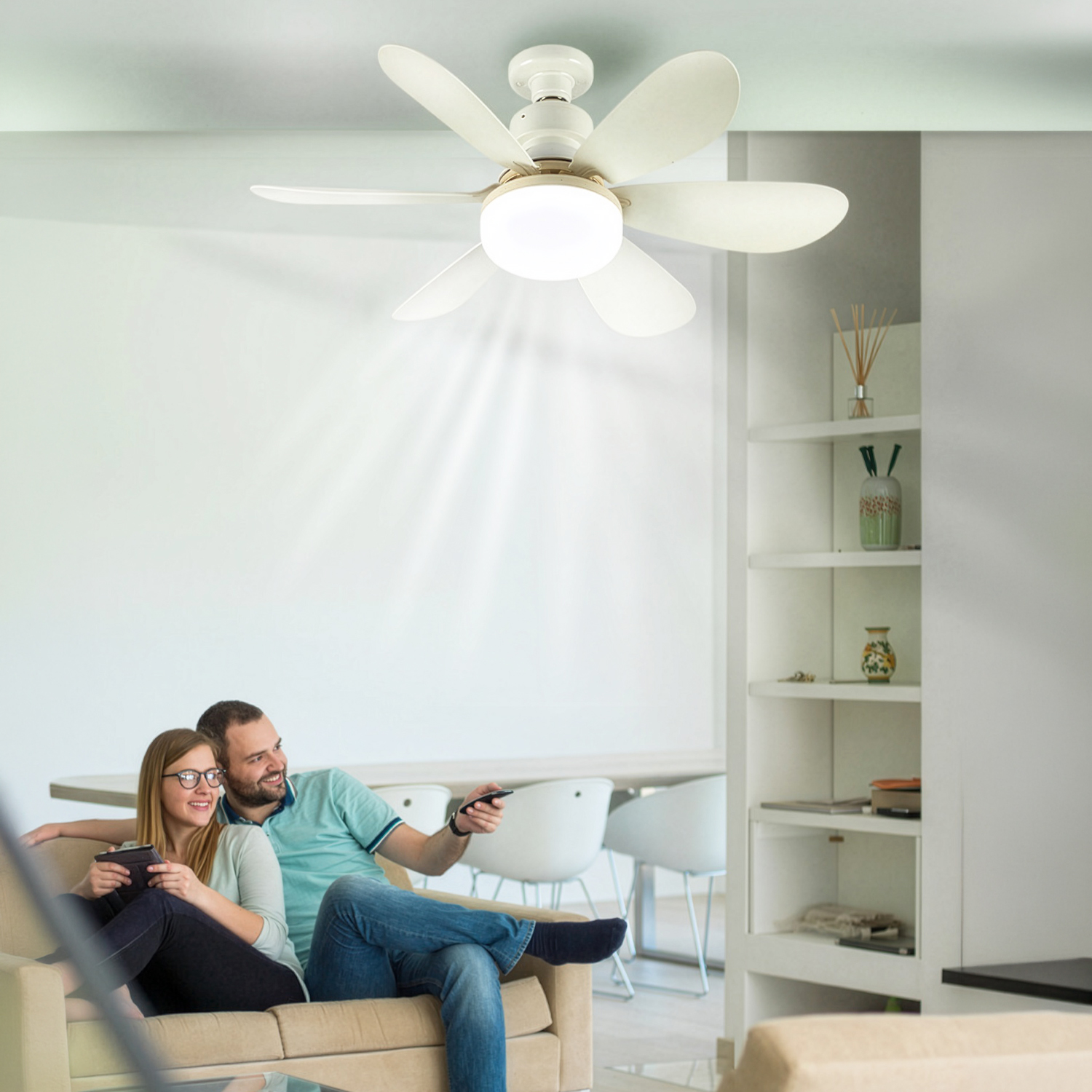 Una pareja se relaja en un sofá bajo un ventilador de techo con luz.