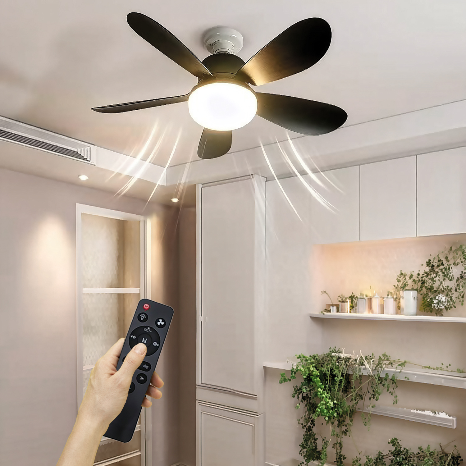 Una mano sostiene un control remoto hacia un ventilador de techo negro con luz, circulando aire en una habitación.
