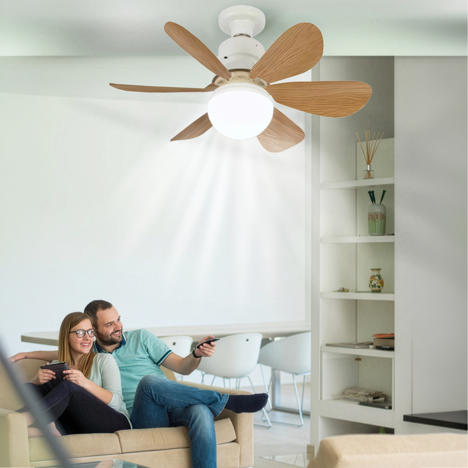 Una pareja se relaja en un sofá, con un ventilador de techo de aspas de madera encima.