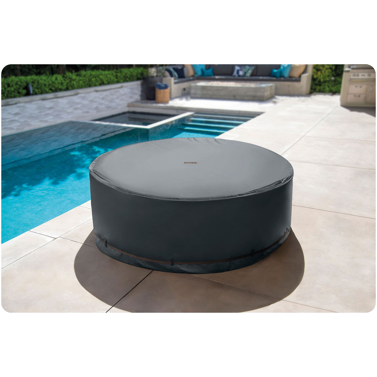Runde graue Whirlpool-Abdeckung auf gepflasterter Terrasse nahe blauem Pool. Außenlounge.