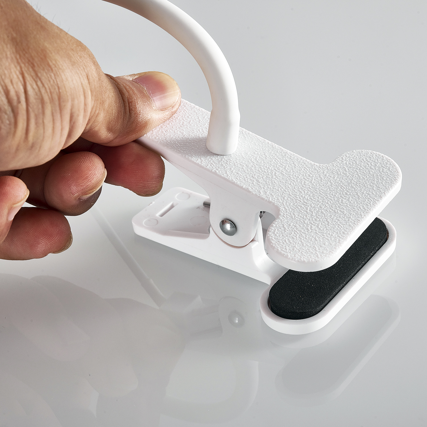 Una mano presionando un clip blanco con inserto negro.