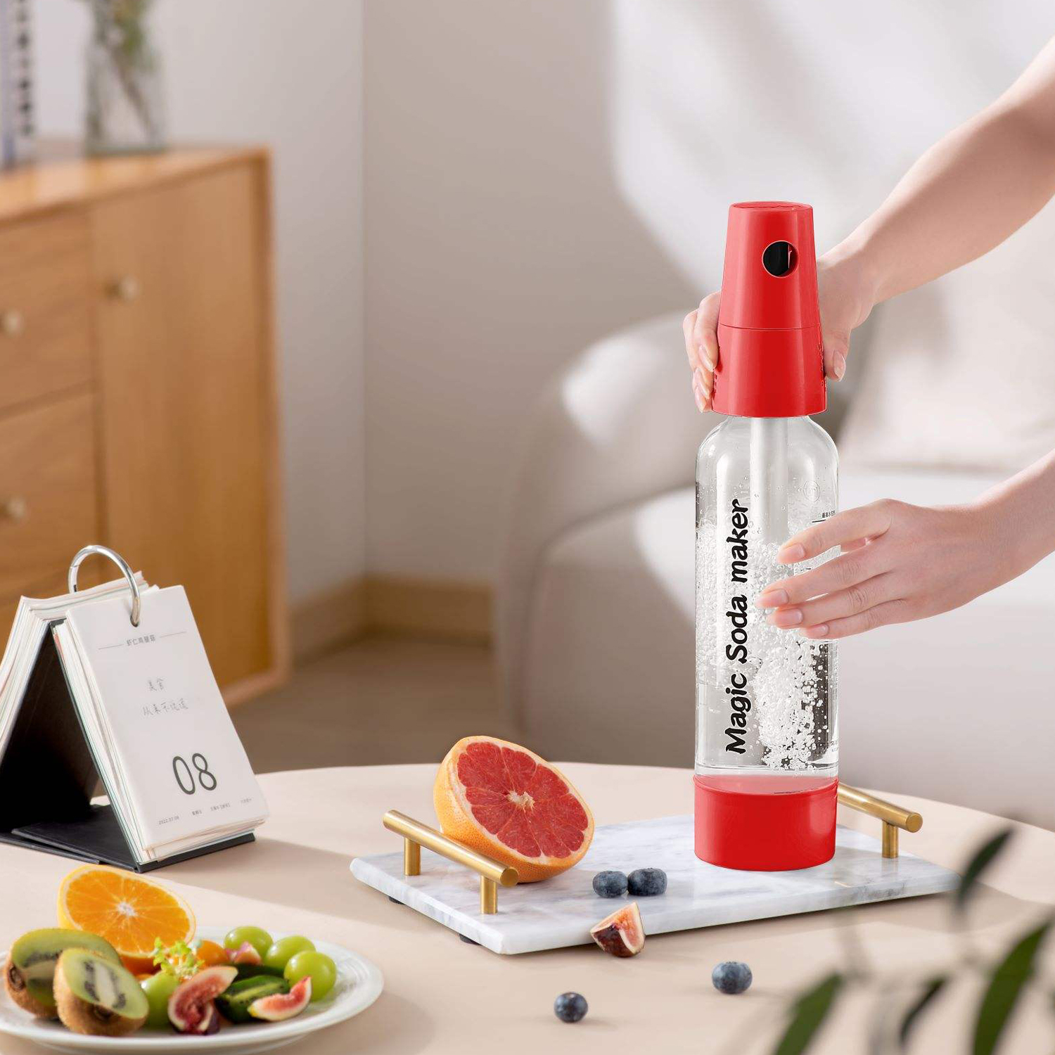Una persona usa un sifón de soda rojo con una ensaladera cerca.