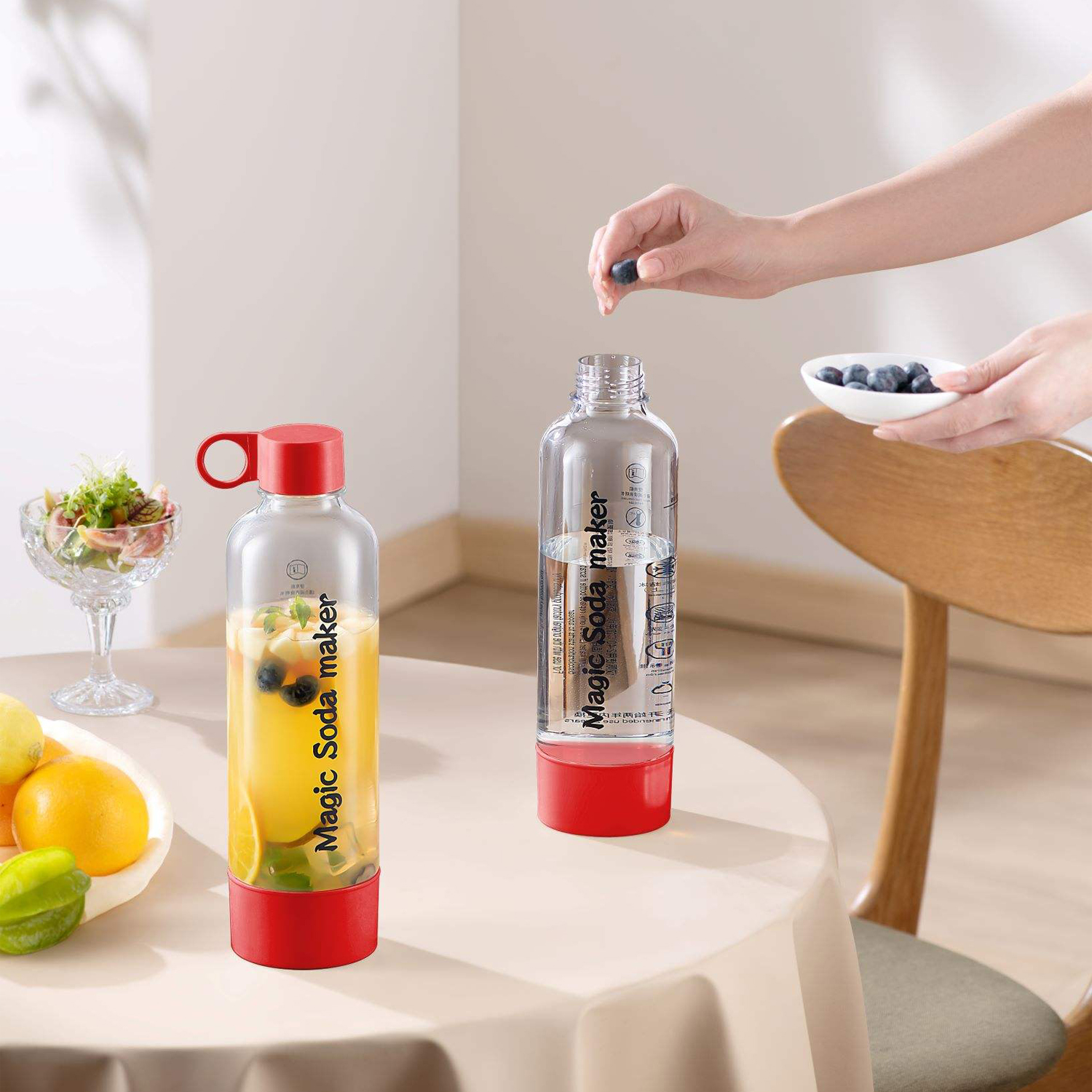 Dos fabricantes de soda con tapas rojas sobre una mesa, uno lleno de fruta y jugo.