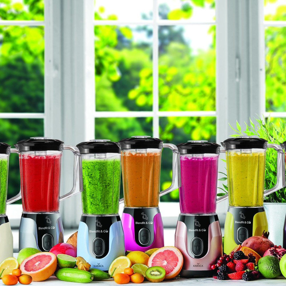 Pencere önünde renkli smoothie'ler ve meyveler olan birkaç blender.