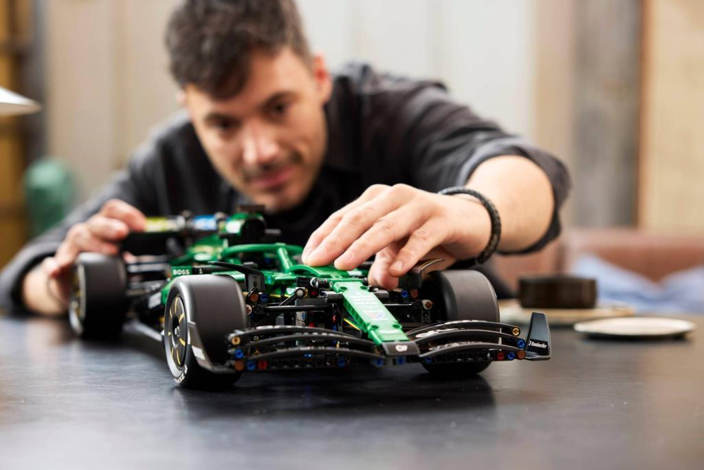Adam yeşil Lego F1 araba monte ediyor. Eller ön kanadı ayarlıyor. Detaylı yapım.