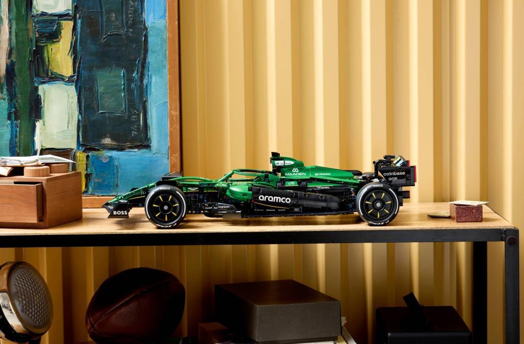 Yeşil Formula 1 yarış arabası modeli rafta, sanat eserinin yanında.
