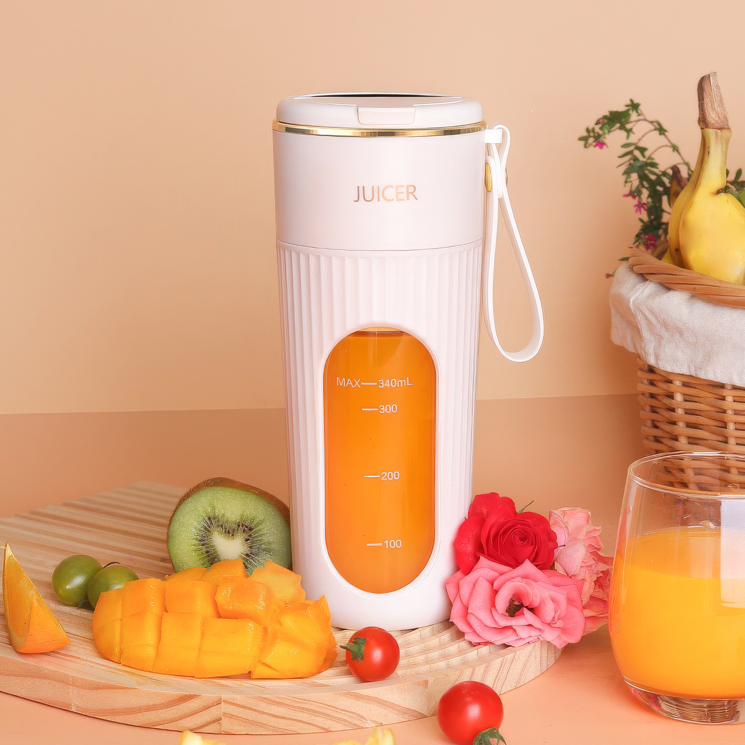 Un exprimidor blanco con líquido naranja, frutas y flores en una tabla de madera.