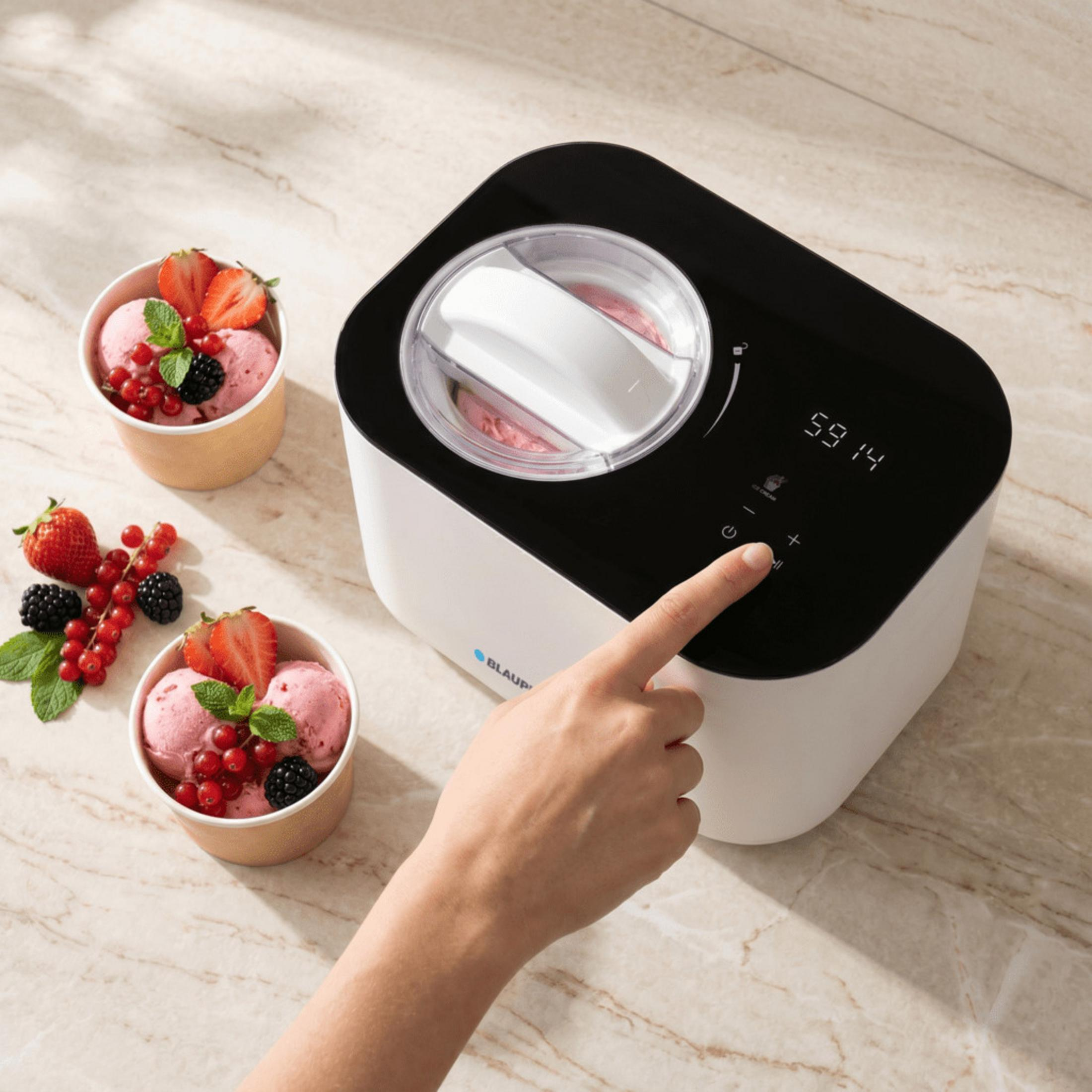 Eiscreme-Maschine mit Beeren und Eiscreme in Bechern, eine Hand bedient sie.