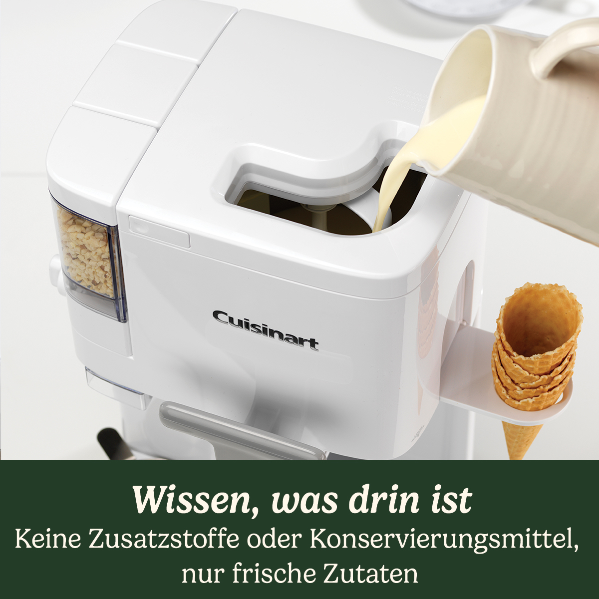 Eine weiße Eismaschine von Cuisinart, die mit Eiscreme gefüllt wird. Daneben stehen Waffelkegel.