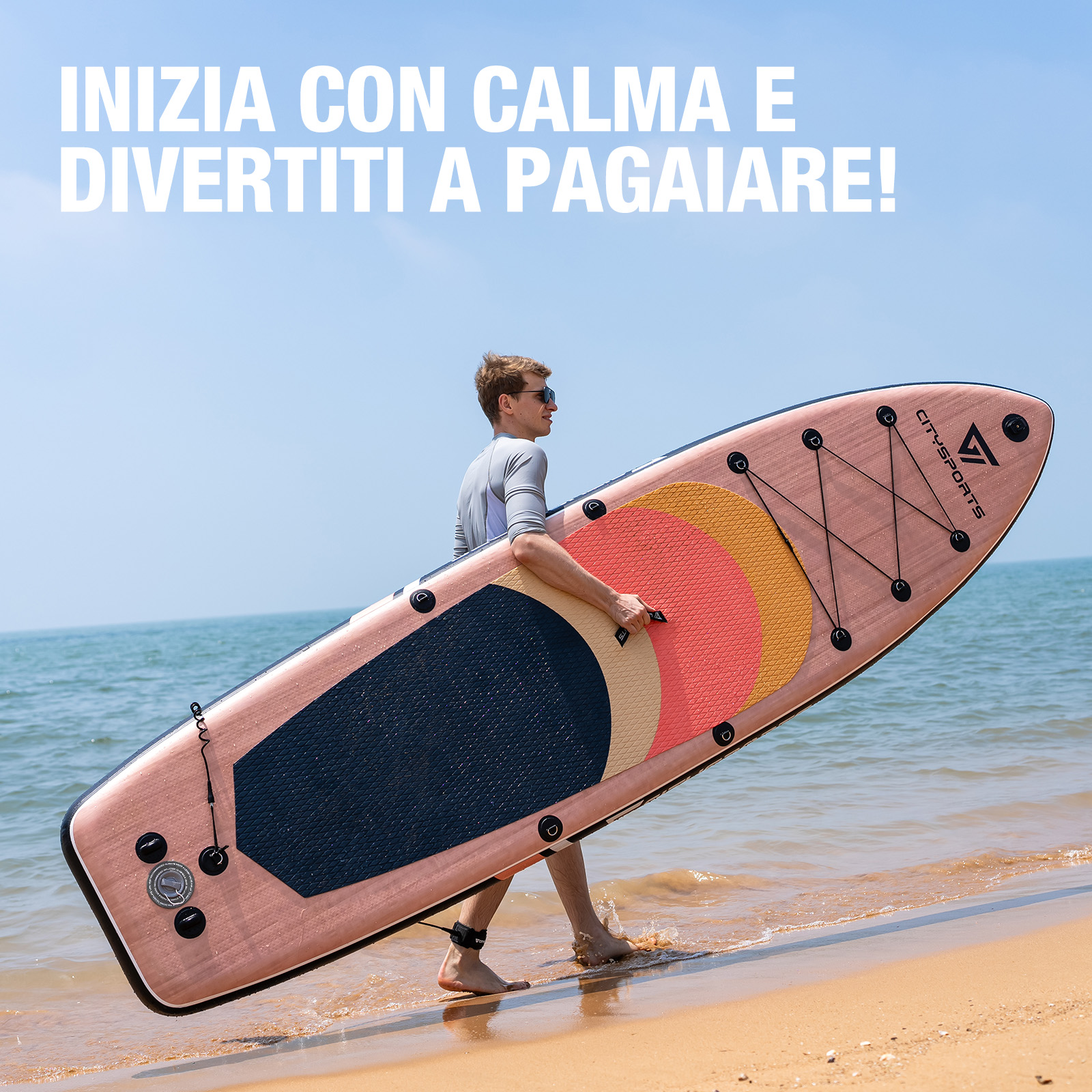 Un uomo porta una tavola da paddle rosa sulla spiaggia.